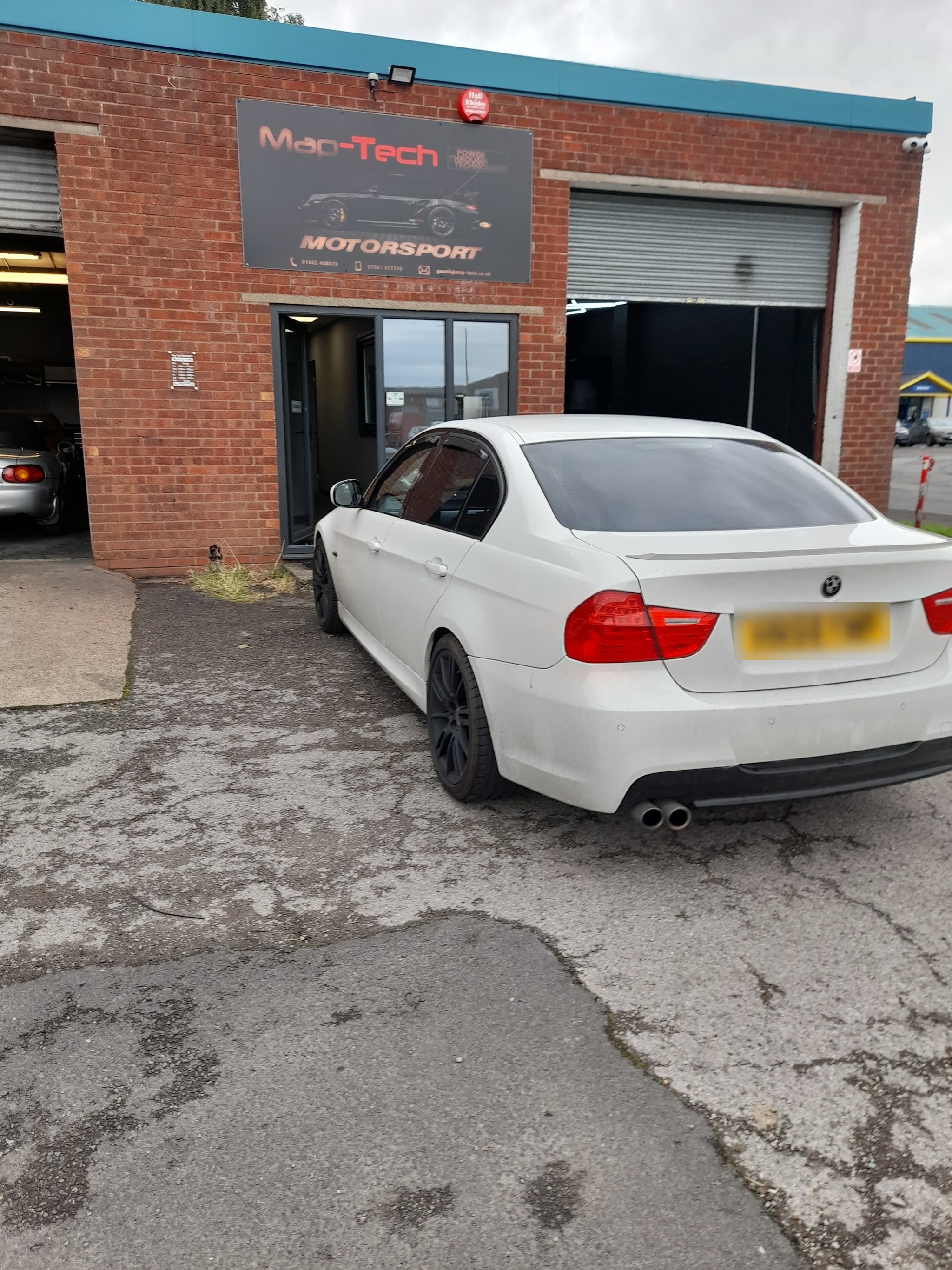 A white BMW 3 Series parked outside the Map-Tech Motorsport unit