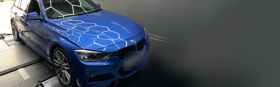 A blue BMW 3 Series on the Map-Tech dyno with the hexagon lights reflected across the car