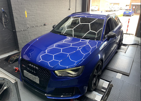 A blue Audi on the Map-Tech dyno with the hexagon lights reflected on its bonnet