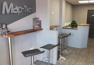 The Map-Tech customer waiting area with bar stools, a counter and the Map-Tech sign